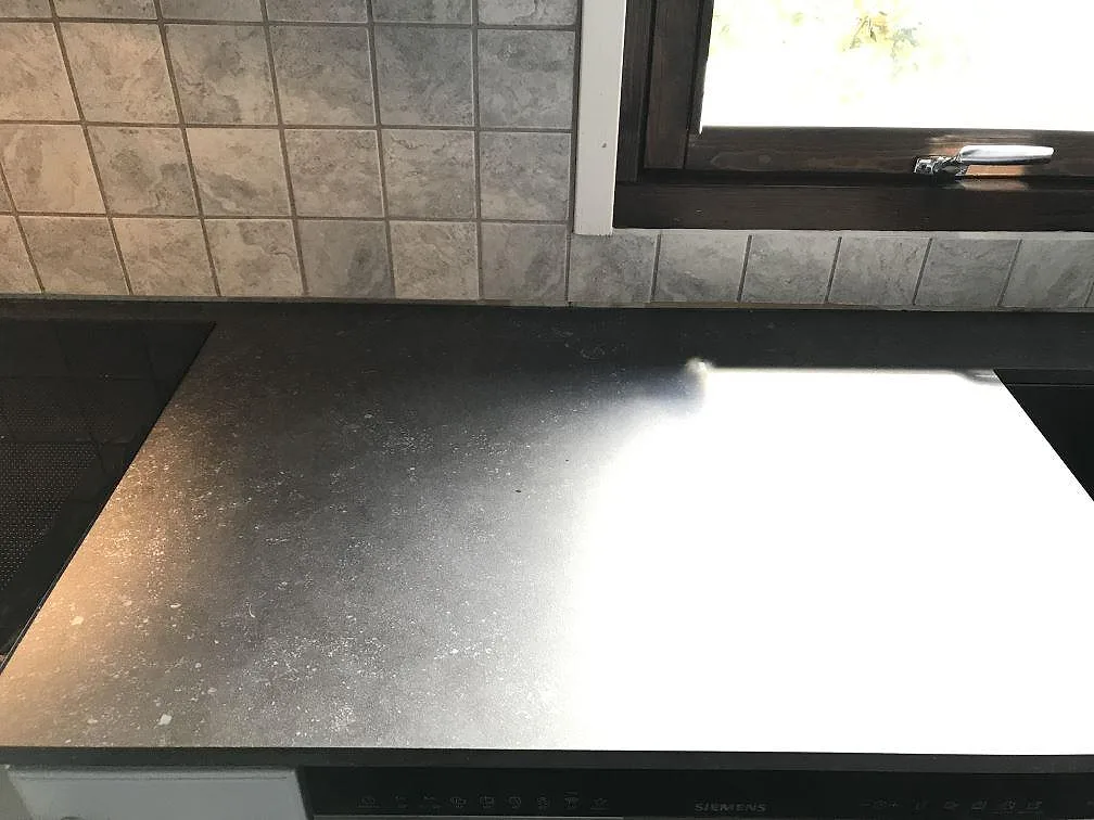 Kök i Vellinge med köksbänkskiva i mörk matt Dekton Fossil längs två väggar, fotat under montering innan rummet var helt inrett.