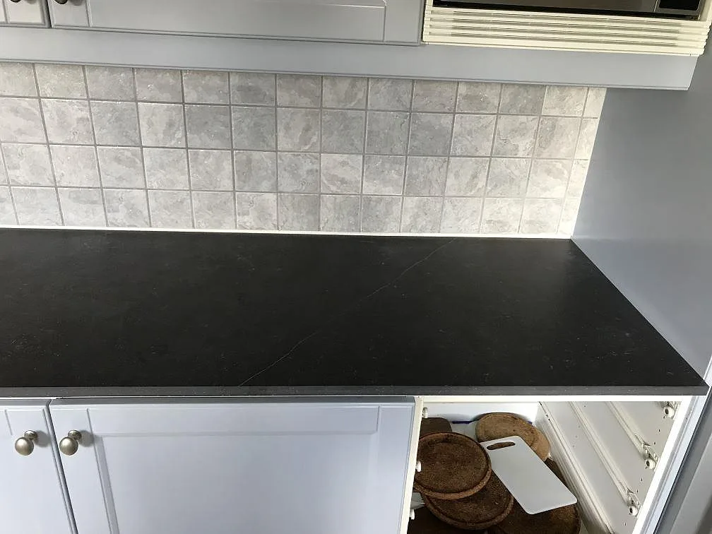 Underlimmad rostfri diskho i köksbänkskiva av mörk Dekton Fossil i ett kök i Vellinge.