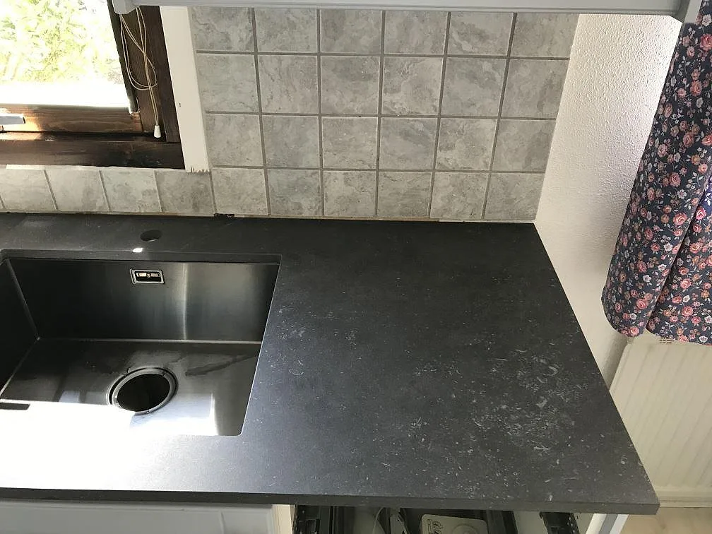 Köksbänkskiva i antracitgrå Dekton Fossil med underlimmad rostfri diskho och fossilliknande spräcklighet i ett kök i Vellinge.