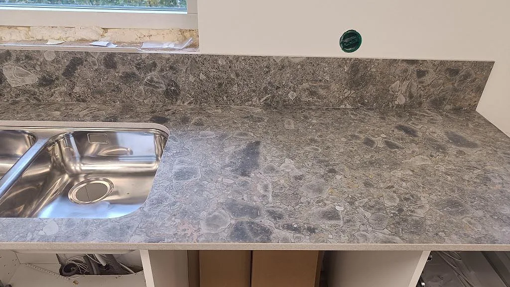 Rak köksbänkskiva i matt Dekton GK07 Ceppo med rostfri diskho och matchande stänkkant i Össjö.