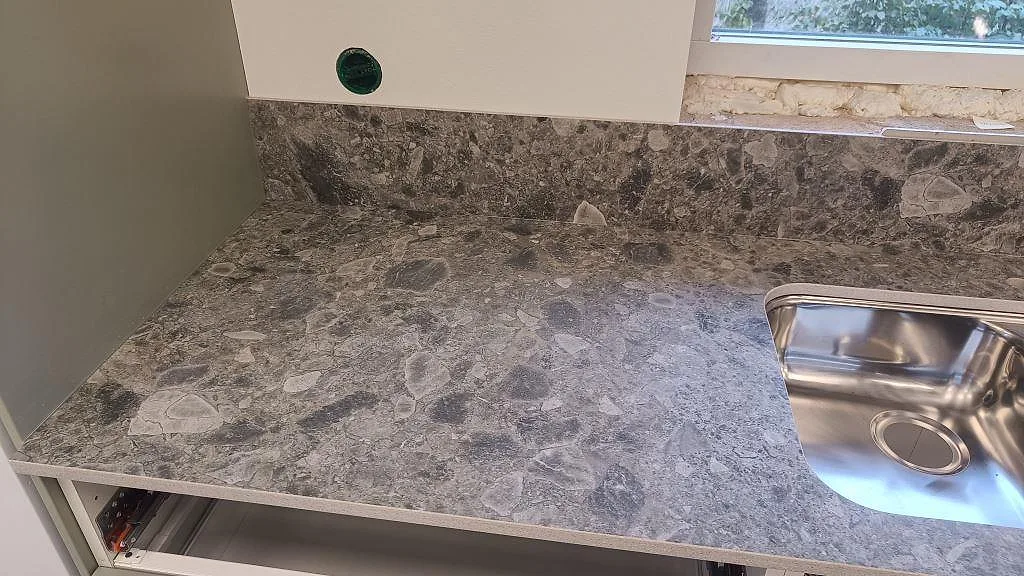 Närbild av matt Dekton GK07 Ceppo med rostfri diskho, grå Ceppo-mönstring och låg stänkkant i Össjö.