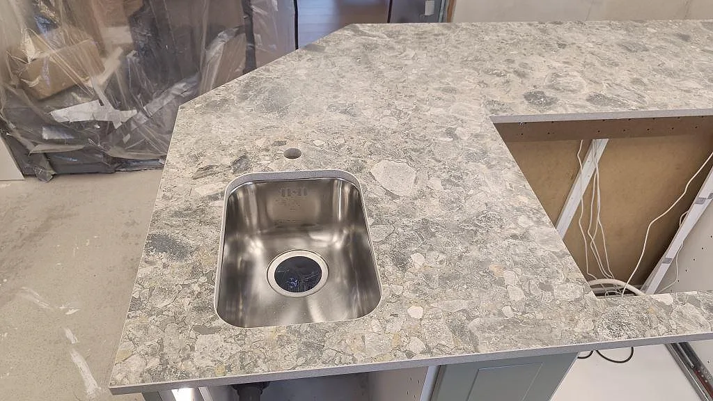 Köksö i matt Dekton GK07 Ceppo med underlimmad enkel rostfri diskho och synlig Ceppo-struktur i Össjö.