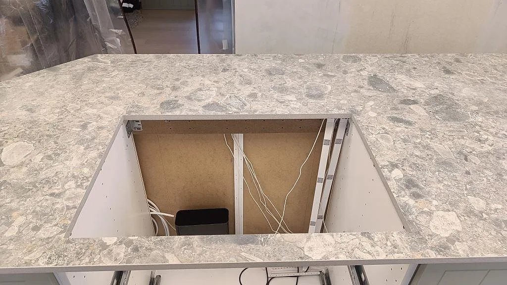 Köksö i matt Dekton GK07 Ceppo med stor urtagning och grå stenstruktur under montering i Össjö.