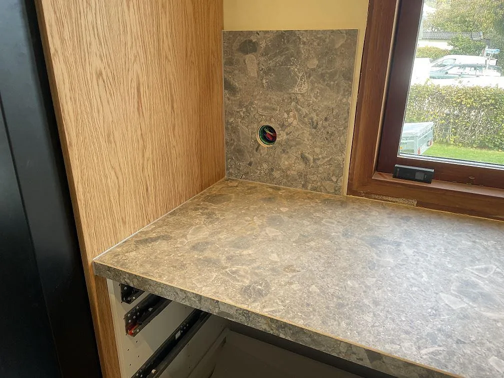 Detalj av matt Dekton GK07 Ceppo vid fönster och träinredning, grå keramisk bänkskiva i Västra Frölunda.