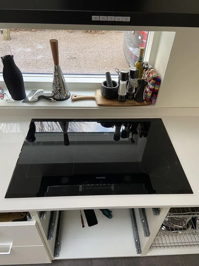 Svart Siemens induktionshäll infälld i polerad bänkskiva av Dekton Halo keramik vid fönstret i ett kök i Lund.