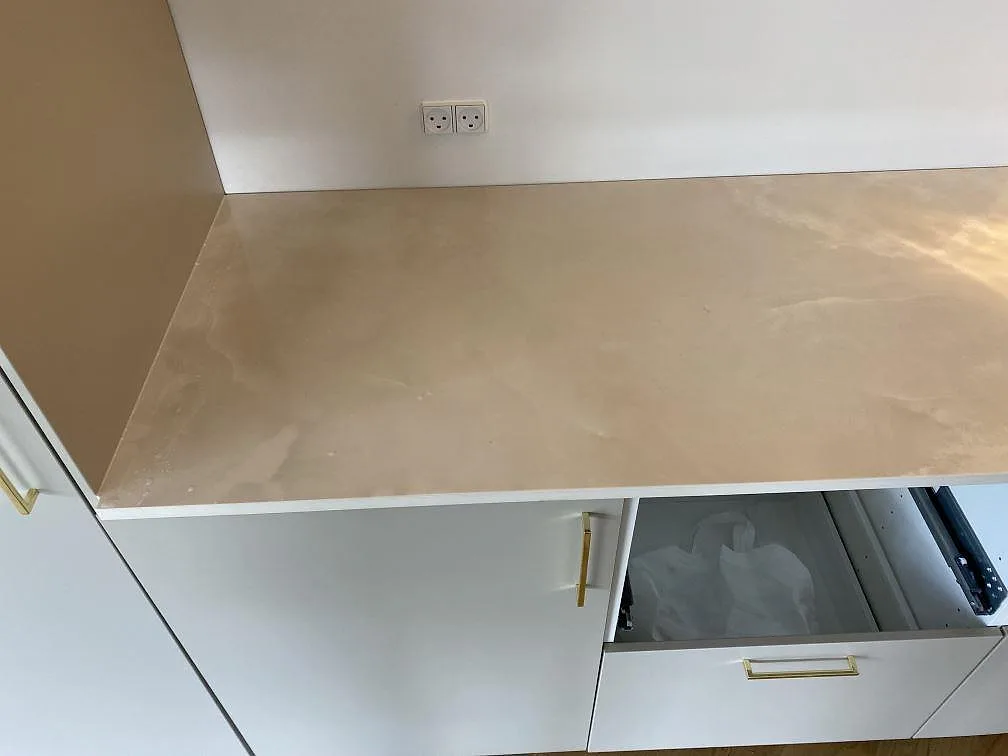 Närbild av polerad Dekton Helena köksbänkskiva i keramik med ljus ådring på vita köksstommar i Espergærde.