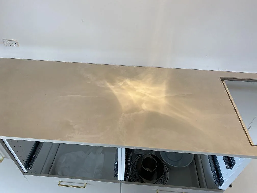 Polerad Dekton Helena bänkskiva med öppen urtagning för häll och ljus marmorliknande ådring i kök i Espergærde.