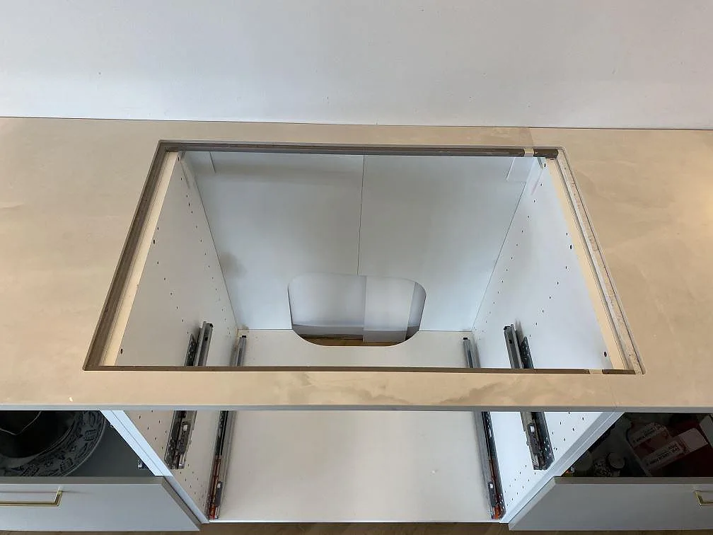Detalj av hällurskärning i 20 mm polerad Dekton Helena keramik på vita köksstommar under montering i Espergærde.
