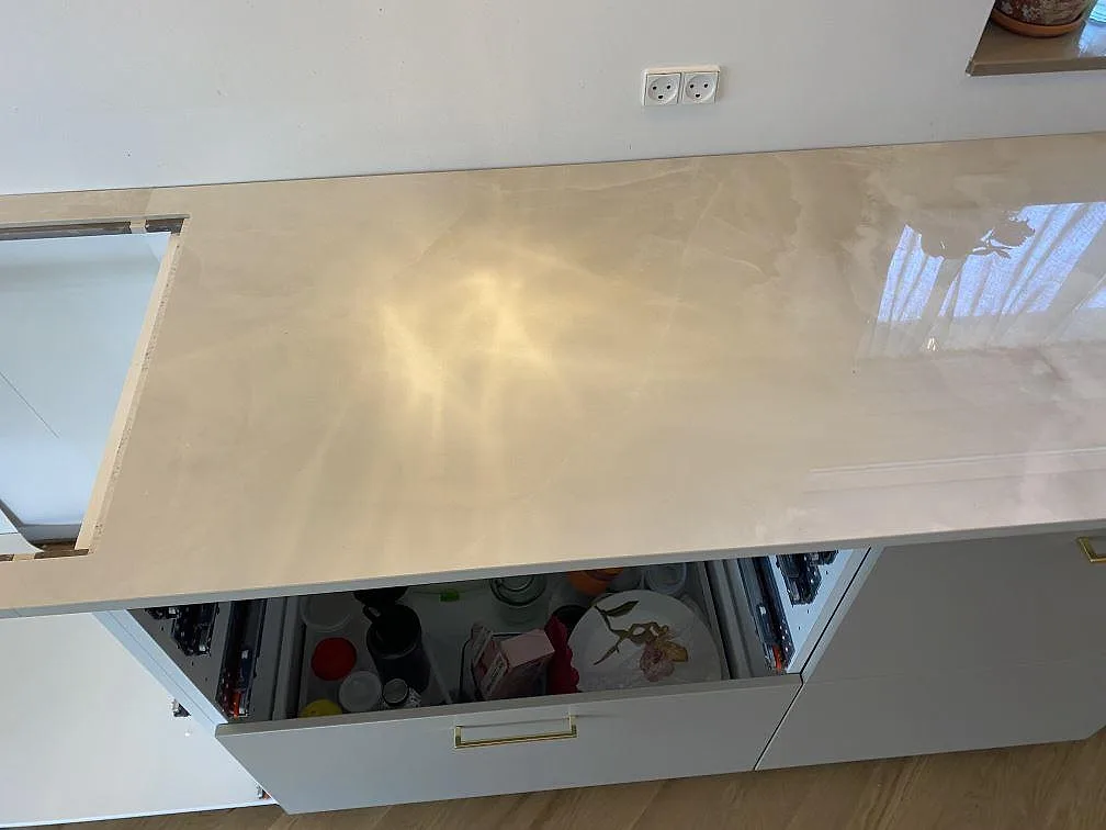 Närbild av polerad Dekton Helena köksbänk med reflekterande yta och öppna lådor i ett kök i Espergærde.