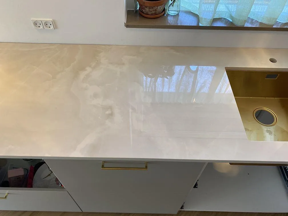 Köksbänkskiva i polerad Dekton Helena keramik med synlig metallfärgad diskho, blandarhål och ljus ådring i Espergærde.