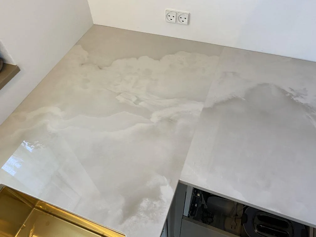Hörn av polerad Dekton Helena köksbänkskiva i keramik med ljus ådring och diskho intill, Espergærde.