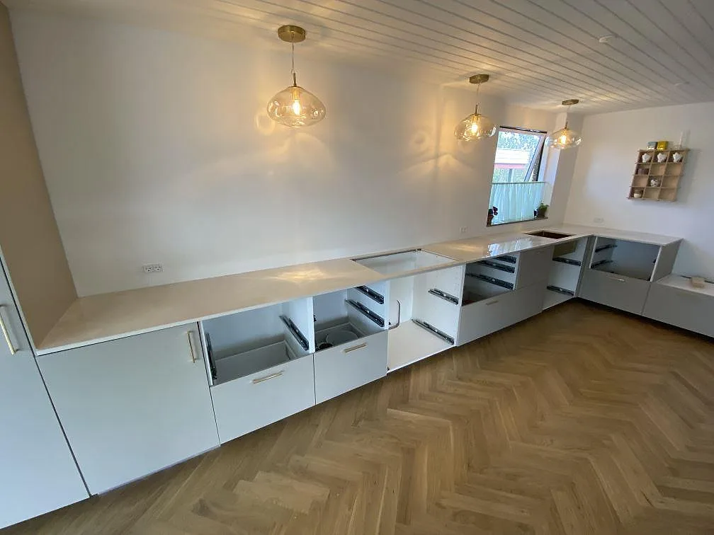 Polerad köksbänkskiva i Dekton Helena keramik, 20 mm, monterad längs en lång vägg med öppen hällurskärning i ett kök i Espergærde.