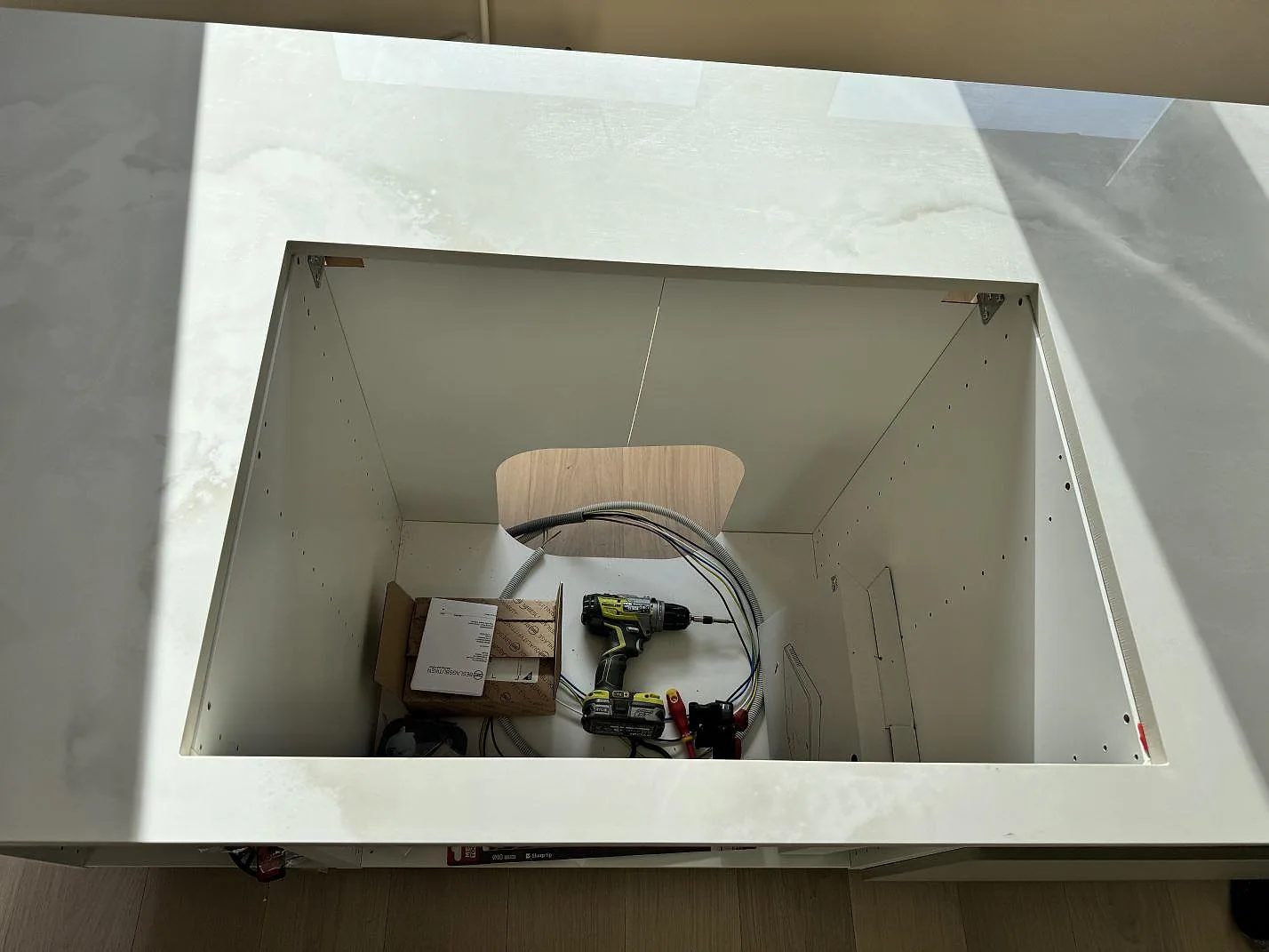 Detalj av rektangulär öppning i polerad Dekton Helena på köksö under montering i Göteborg.