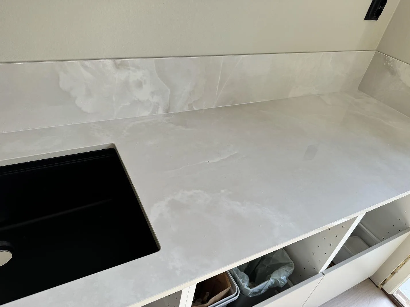 Köksbänkskiva i polerad Dekton Helena med svart diskho och lågt stänkskydd vid väggen i Göteborg.