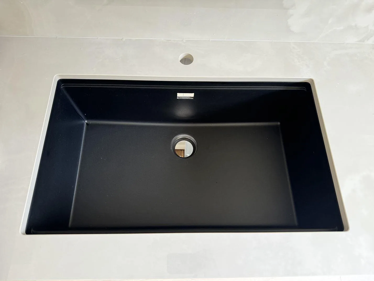 Närbild på svart diskho i polerad Dekton Helena med blandarhål och ljus keramik i Göteborg.