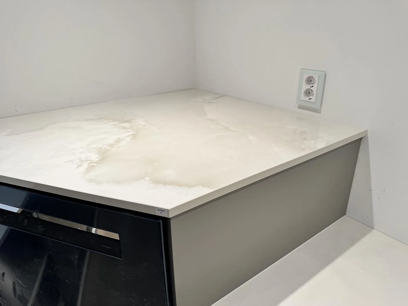 Köksbänkskiva i polerad Dekton Helena med ljus ådring och vägguttag ovanför stenen i Helsingborg.