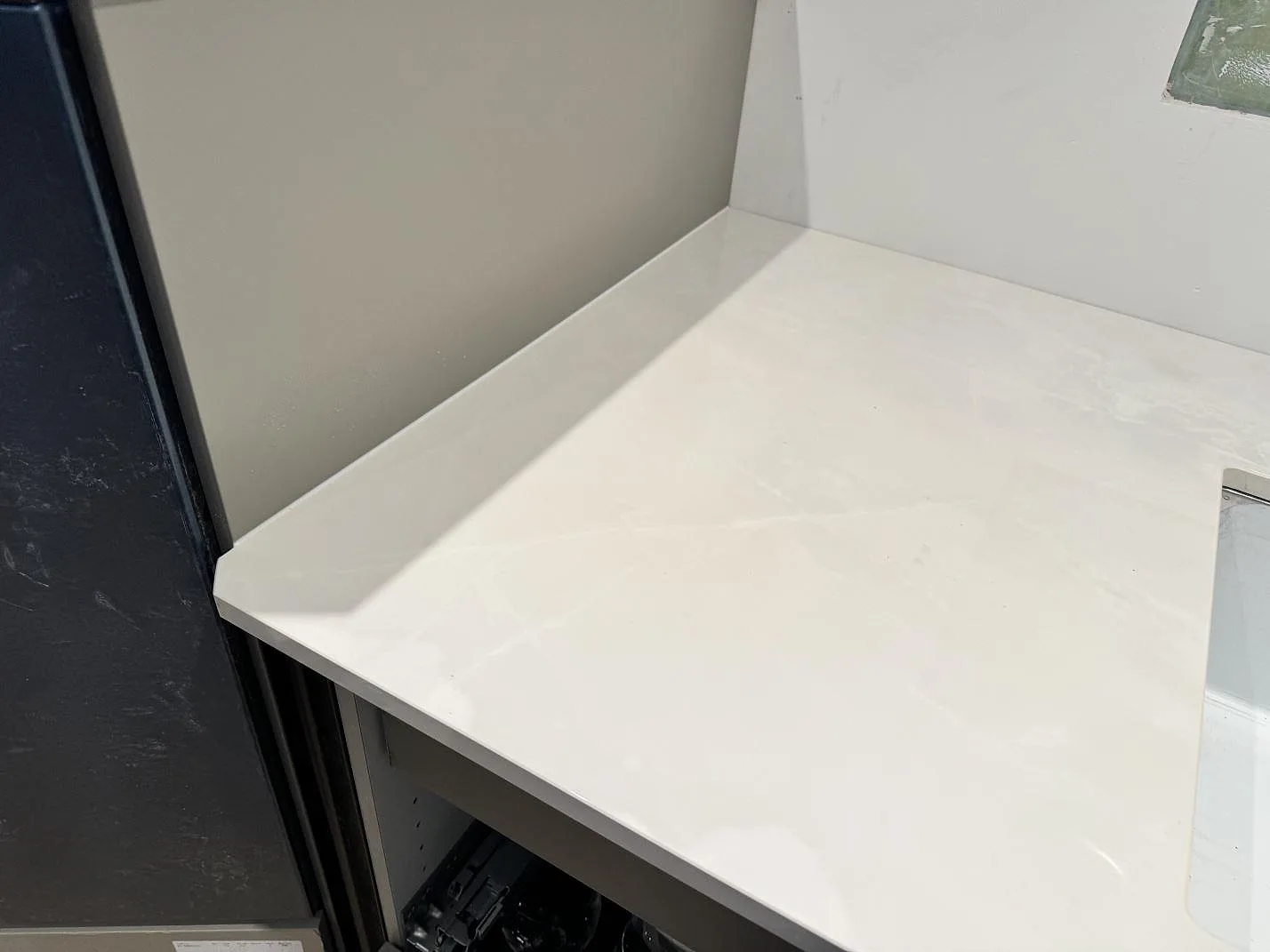 Sidoyta i polerad Dekton Helena vid köksstommar och vit vägg, fotograferad under montering i Helsingborg.
