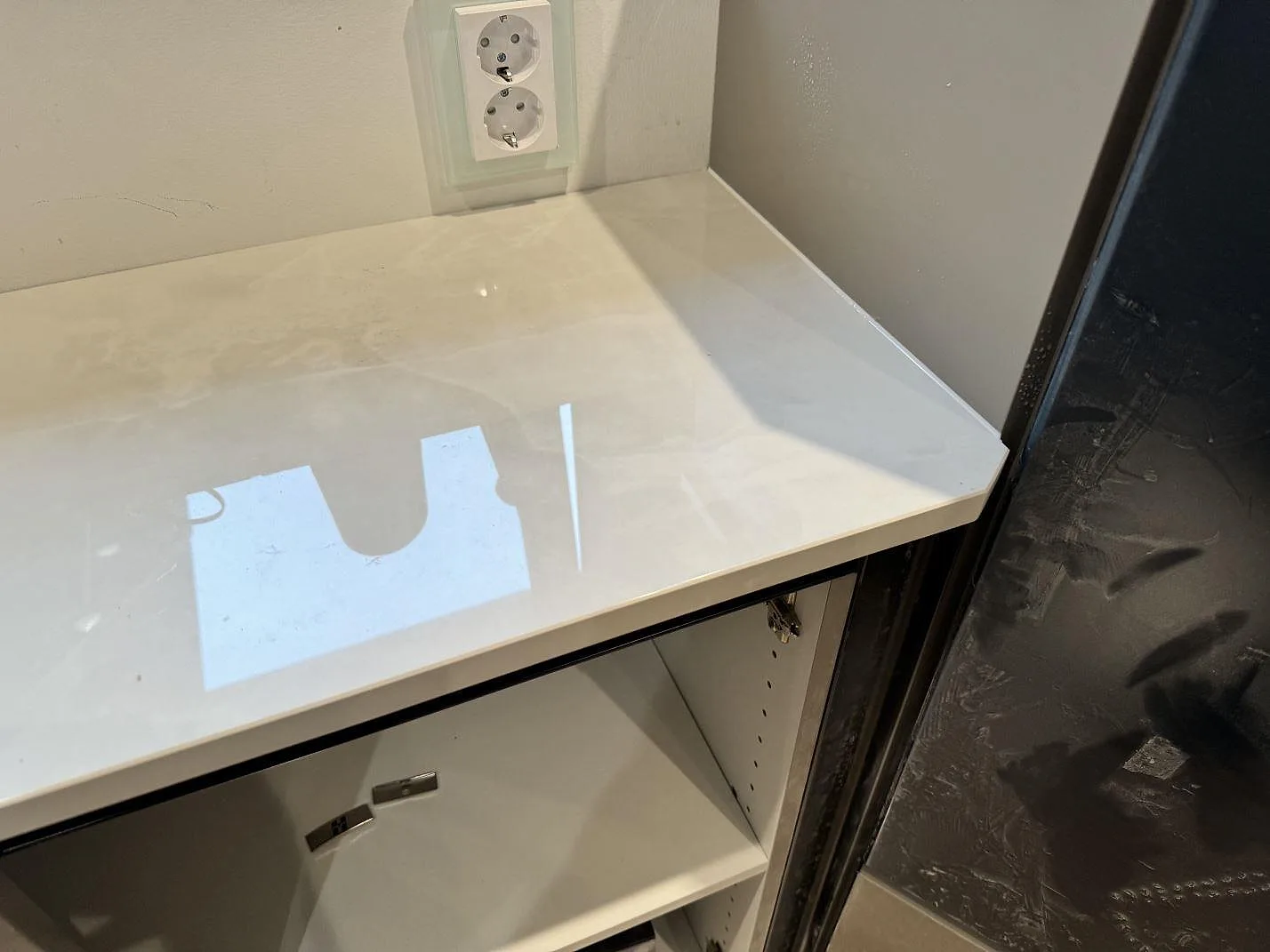 Blank polerad Dekton Helena med reflektioner och ljus marmorering intill mörk köksinredning i Helsingborg.