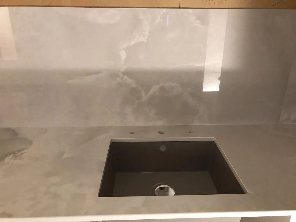 Underlimmad komposithoar i grått i en köksbänkskiva av Dekton Helena, med borrade hål för blandare, i ett kök i Lessebo.