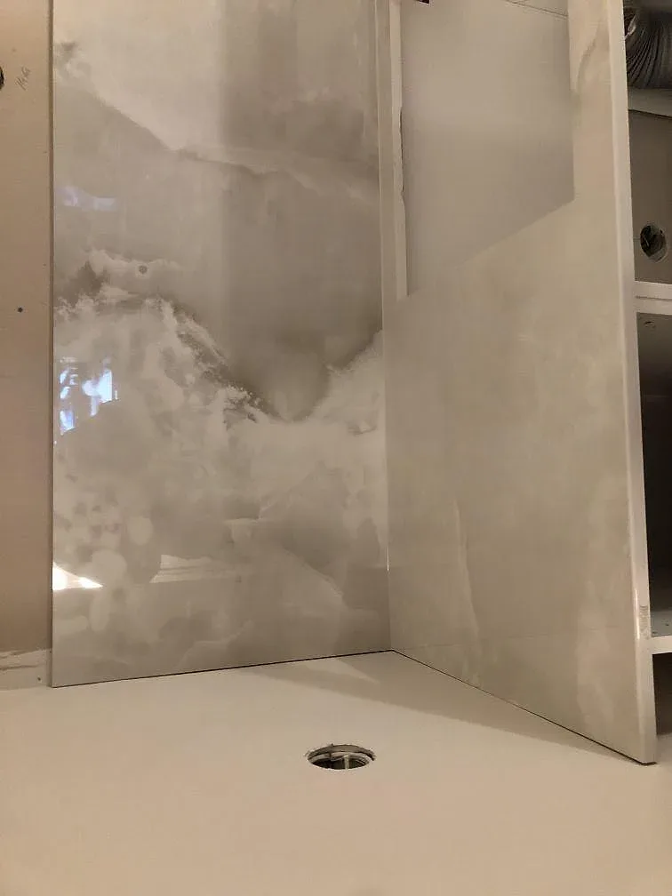 Stänkpanel och bänkskiva i polerad Dekton Helena med onyxlik ådring längs en köksvägg i Lessebo.