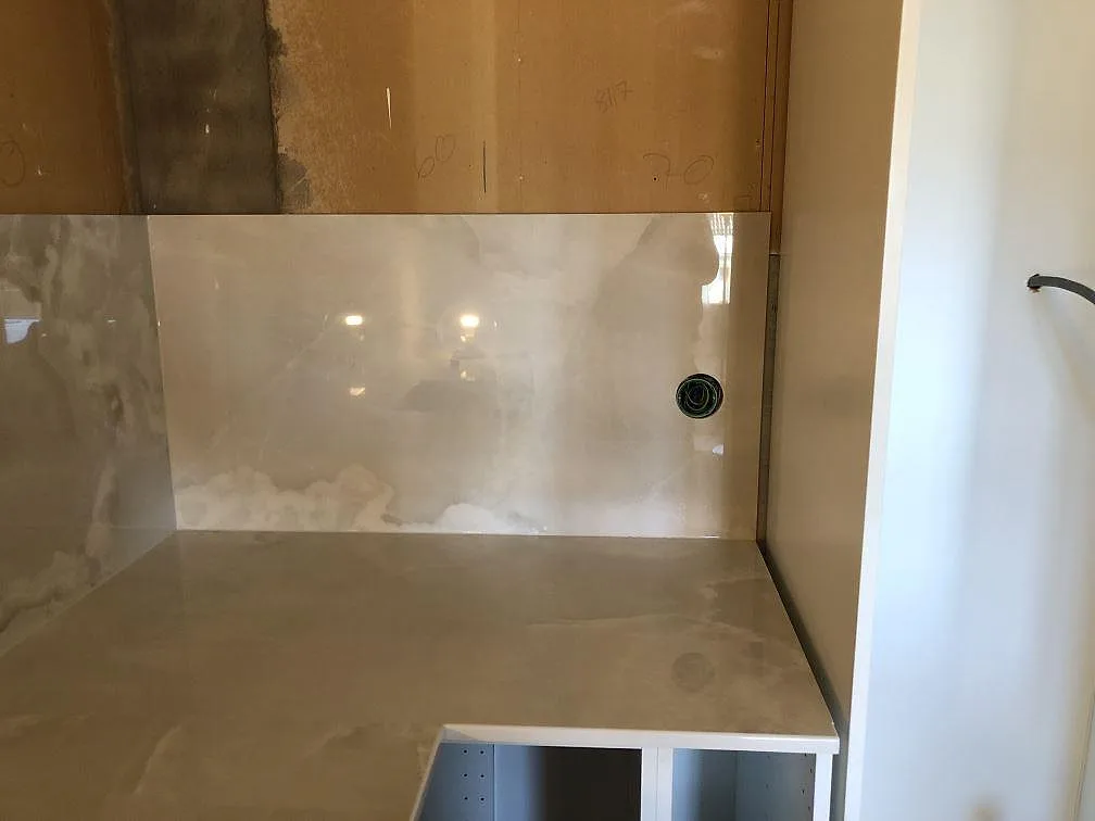 Köksbänkskiva i Dekton Helena med högblank stänkpanel i samma keramik och ett borrat blandarhål, monterad i ett kök under installation i Lessebo.