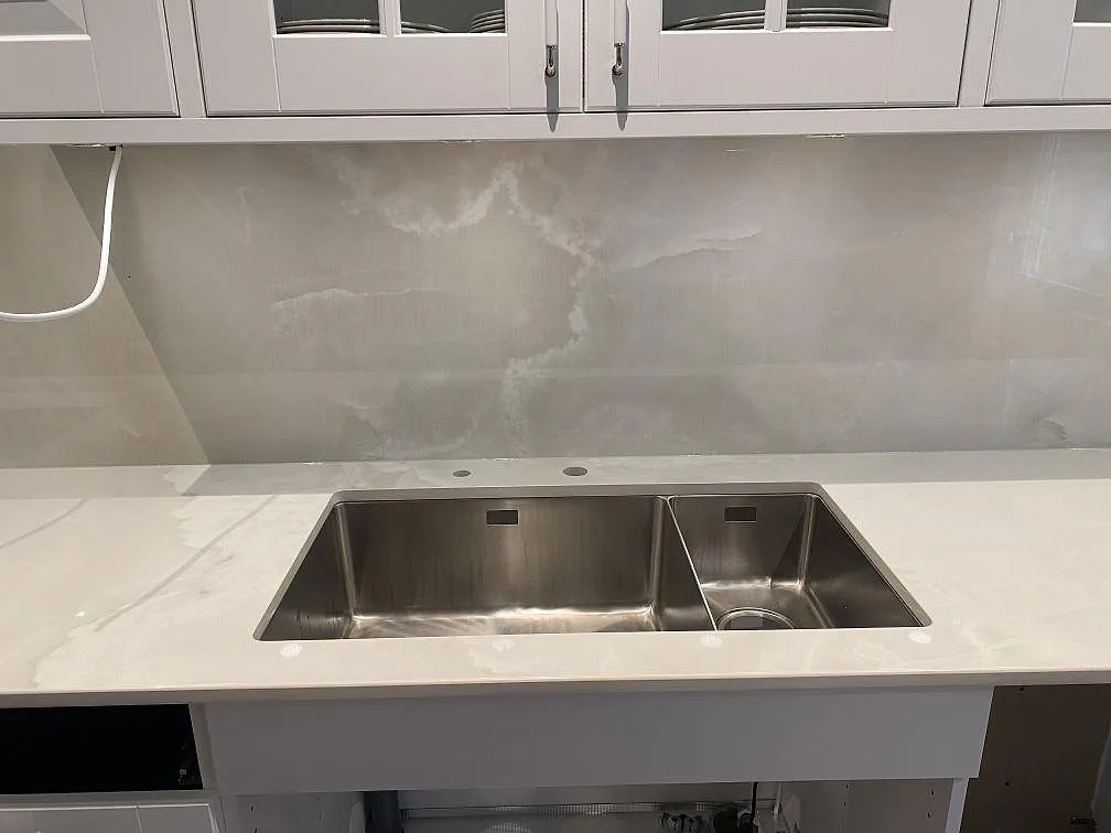 Köksbänkskiva i Dekton Helena med underlimmad rostfri diskho och matchande stänkvägg i gräddvit polerad keramik i Ljungby.