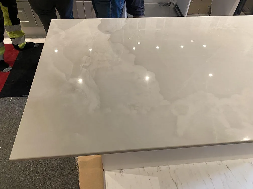 Polerad köksö i Dekton Helena, gräddvit keramik i marmorlook med molnådring, sedd ovanifrån i ett kök i Ljungby.