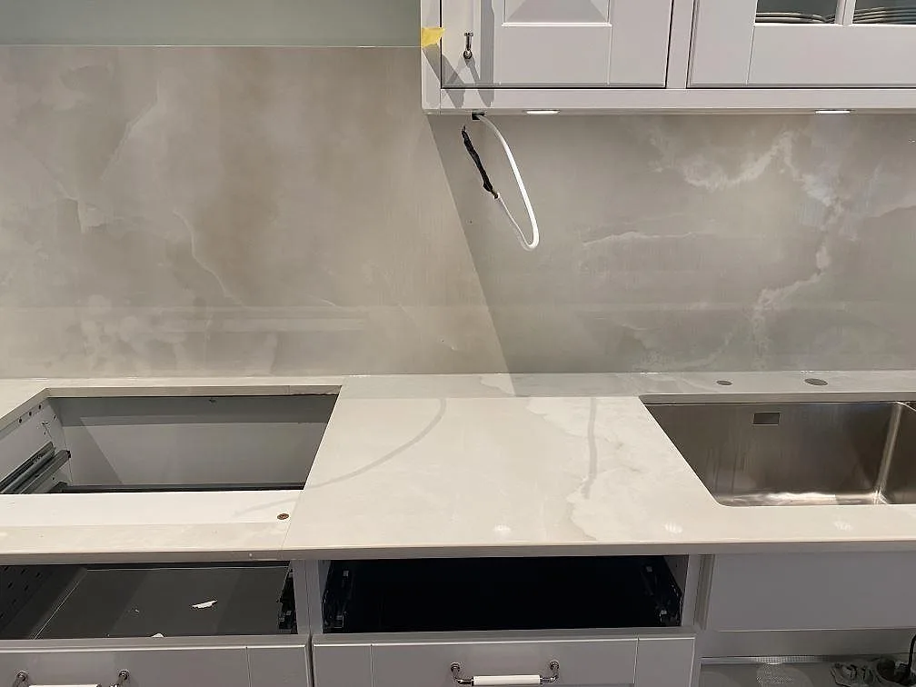 Köksbänkskiva i Dekton Helena med underlimmad rostfri diskho, urtag för häll och heltäckande stänkvägg i polerad keramik i ett kök i Ljungby.