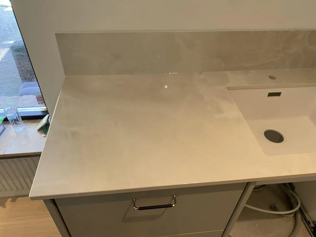 Bänkskiva i Dekton Helena keramik med underlimmad ljus diskho och stänkkant vid fönster i ett kök i Malmö.