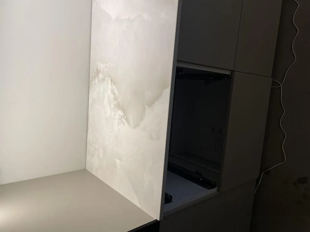 Köksbänkskiva i vit Dekton Helena keramik mot vägg med öppna stommar under montering i Ramlösa.