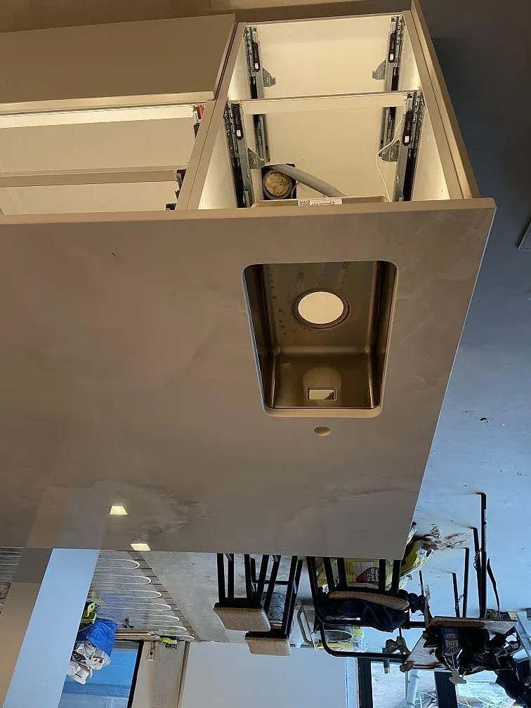 Bänkskiva i polerad Dekton Helena med nedfälld diskhoursparning på köksön i ett kök i Ramlösa.