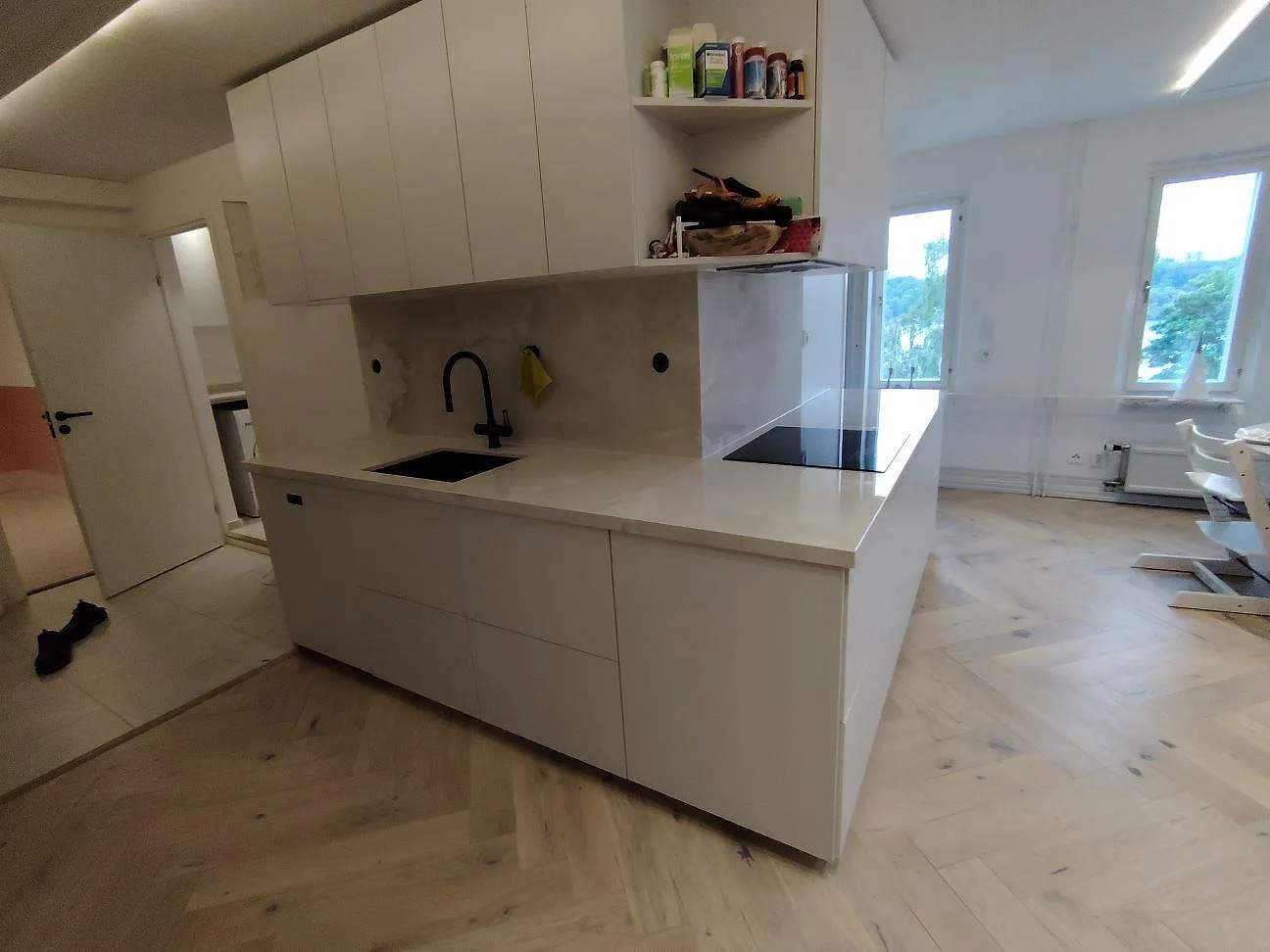 Bred köksvy med Dekton Helena i polerad keramik som bänkskiva och stänkskydd, svart blandare, diskho och häll i Stockholm.