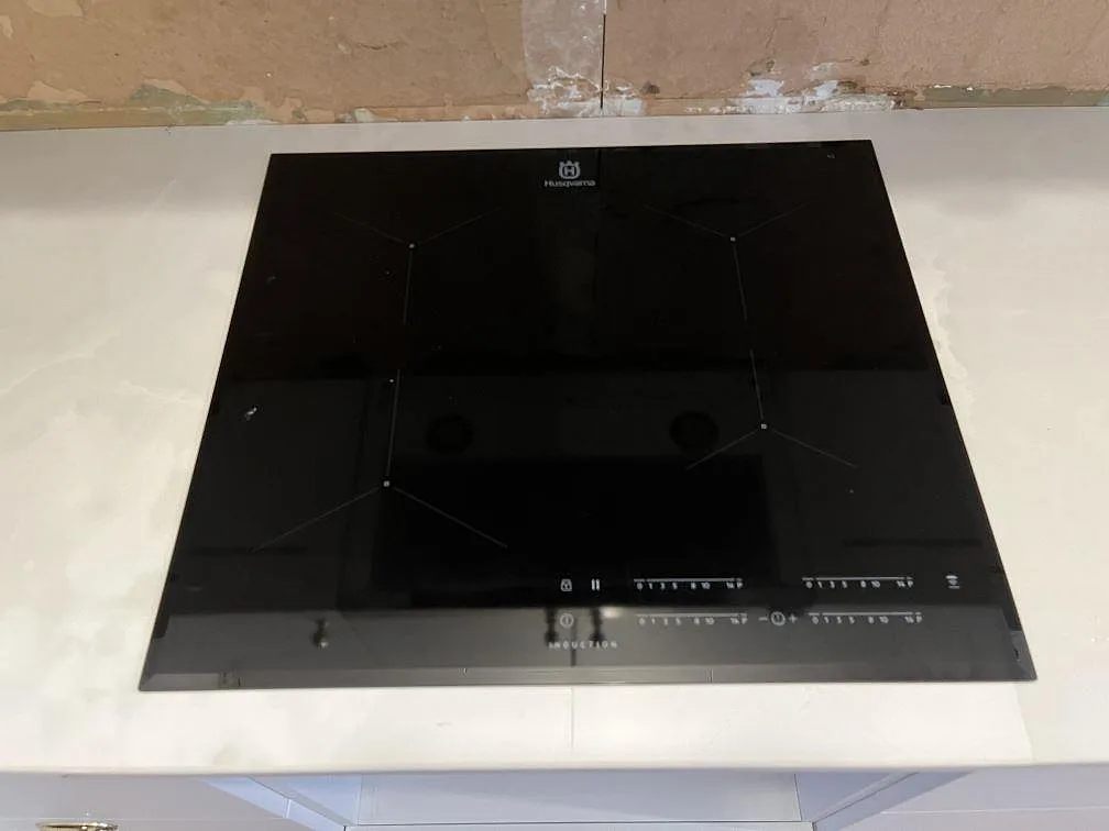 Svart induktionshäll monterad i polerad Dekton Helena keramik på köksbänkskiva i Storebro.