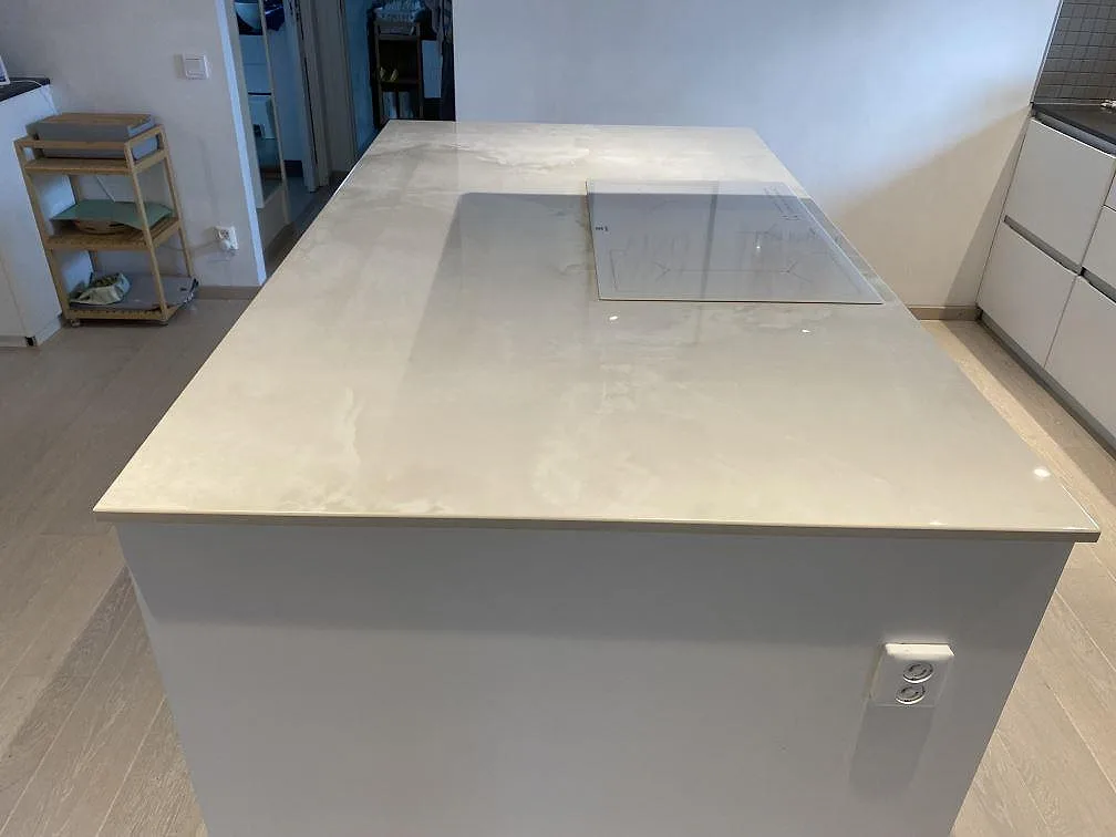 Köksö med polerad Dekton Helena och glasinduktionshäll i ett kök i Trelleborg.