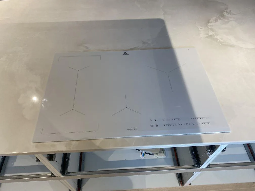 Detalj av polerad Dekton Helena runt glasinduktionshällen på köksön i Trelleborg.