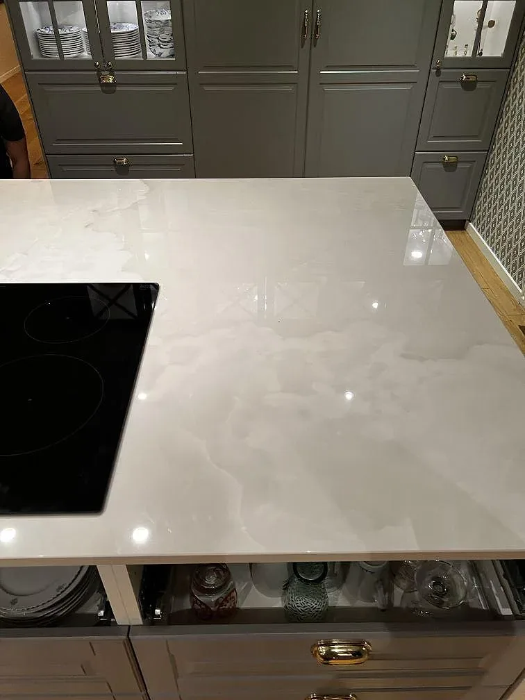 Köksö i polerad Dekton Helena keramik med svart häll och ljus marmorerad yta i ett kök i Växjö.