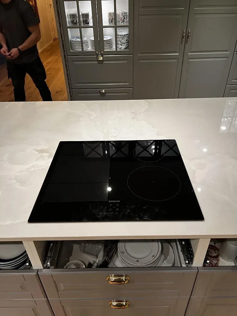 Polerad Dekton Helena bänkskiva med svart häll, grågröna vitrinskåp och blank ådring i Växjö.
