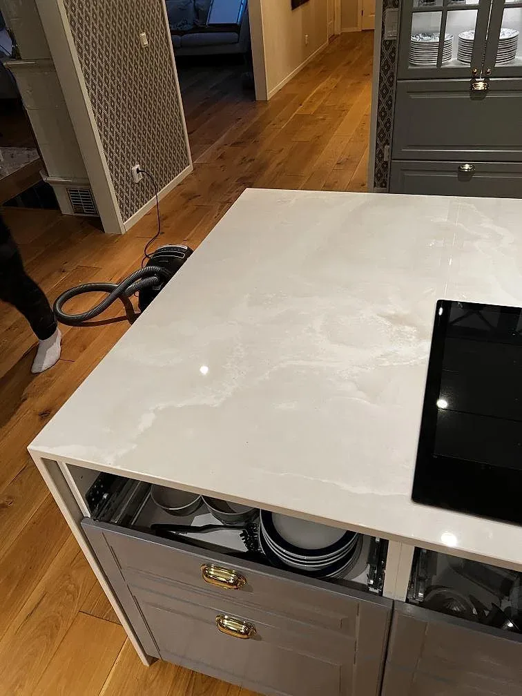 Översikt av vit Dekton Helena köksö med häll, polerad yta och monteringsverktyg i köket i Växjö.