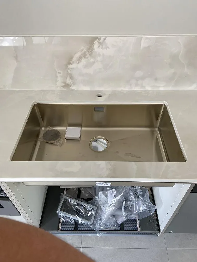 Infälld svart häll i en polerad Dekton Helena-bänkskiva med ljus ådring i ett kök i Ystad.