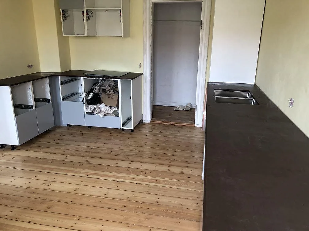 Mörkbrun Dekton Kadum köksbänkskiva med induktionshäll på köksön i ett kök under inredning i København NV.