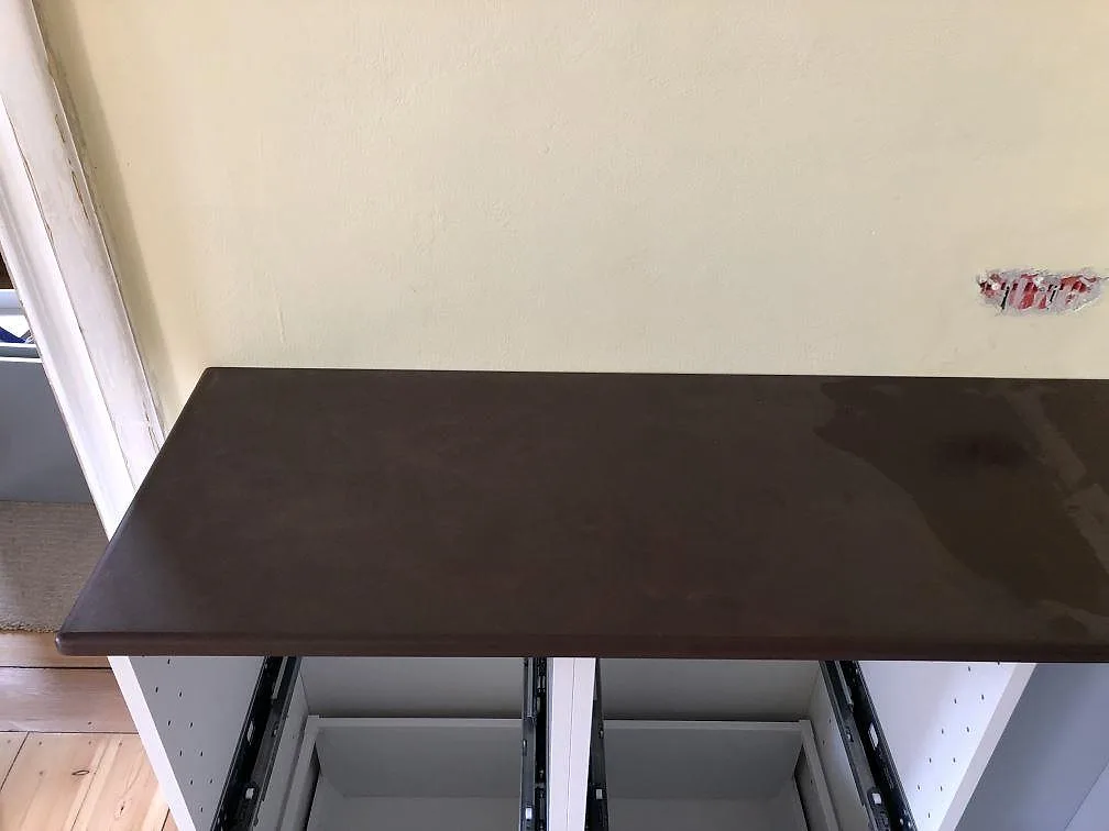 Topdvy av en matt mörkbrun Dekton Kadum köksbänkskiva ovanpå öppna stommar i ett kök i København NV.