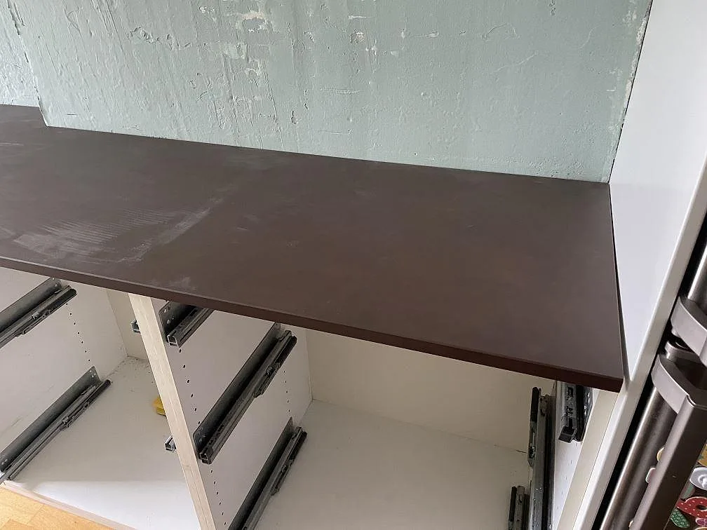 Rak köksbänkskiva i matt Dekton Kadum mot salviagrön vägg och vita stommar i Mölndal.