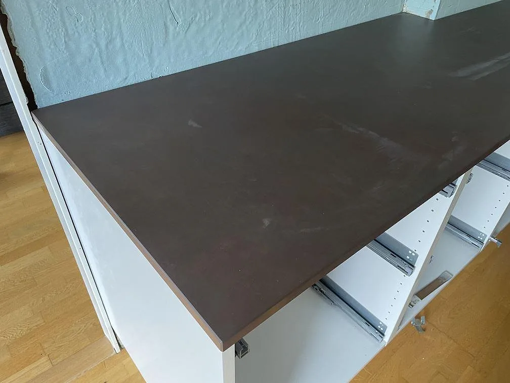 Detalj av mörkbrun matt Dekton Kadum bänkskiva monterad på vita köksstommar i Mölndal.