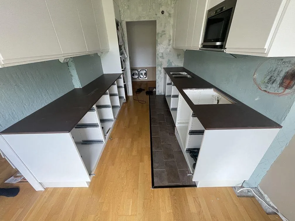 Köksbänkskiva i matt Dekton Kadum, mörkbrun keramik, med dubbel rostfri diskho i ett kök under montering i Mölndal.