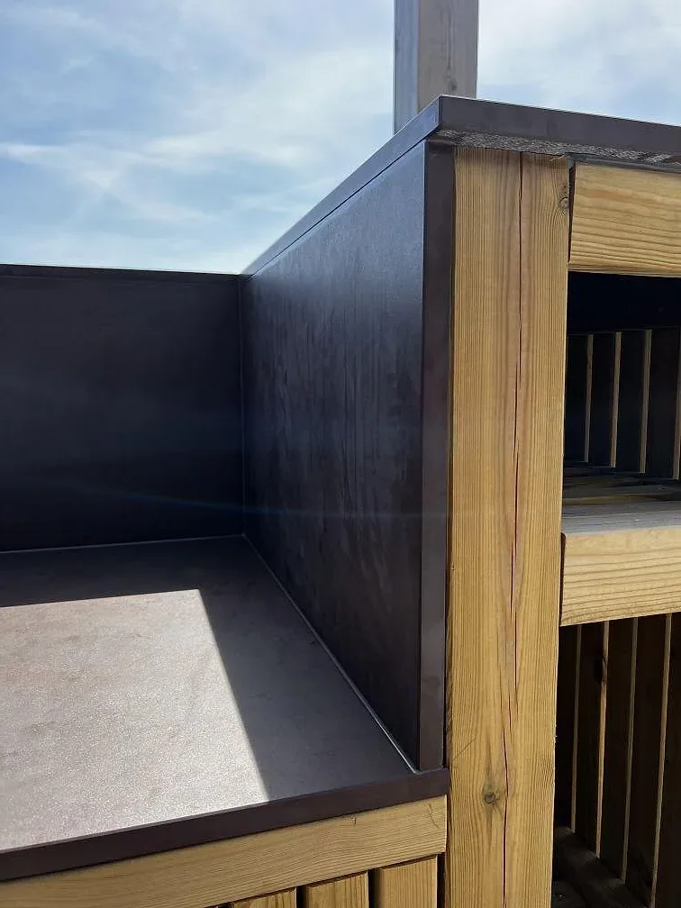 Sidovy av Dekton Kadum i matt keramik som bänkskiva och beklädnad på en träklädd uteköksbas i Påarp.