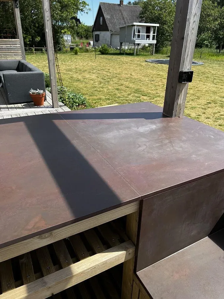Bred arbetsyta i matt Dekton Kadum keramik på ett träklätt utekök med utsikt mot trädgården i Påarp.