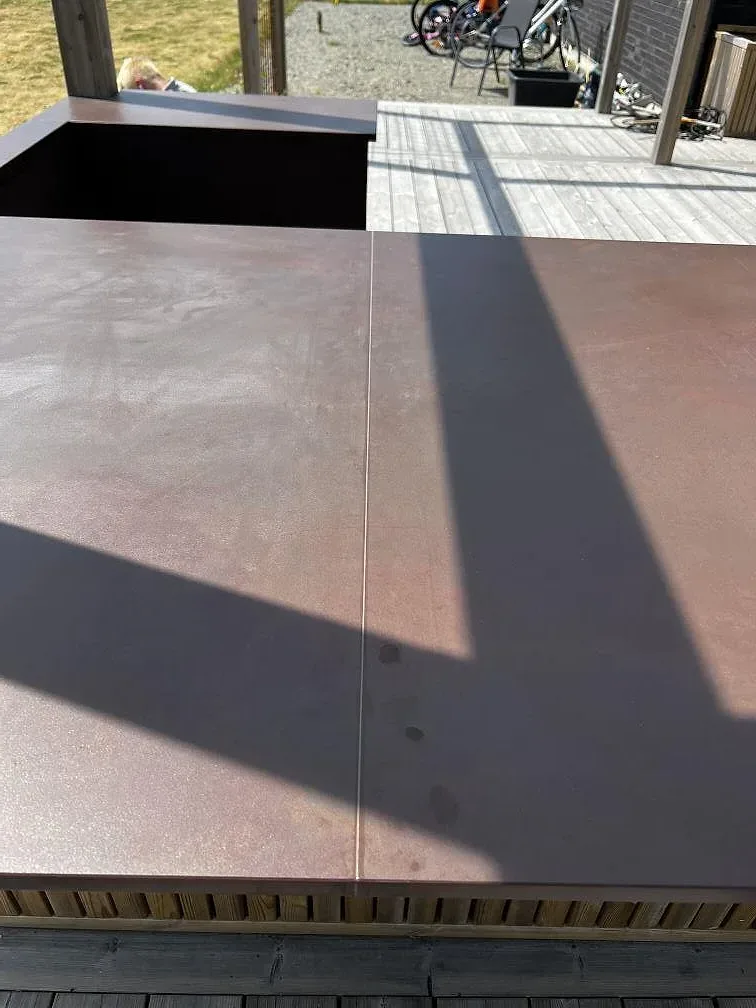 Ovanvy av matt Dekton Kadum bänkskiva med skarv och varm brun yta i ett utekök i Påarp.