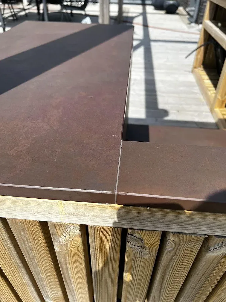Närbild på skarv och urtag i matt Dekton Kadum keramik på en träklädd uteköksbar i Påarp.