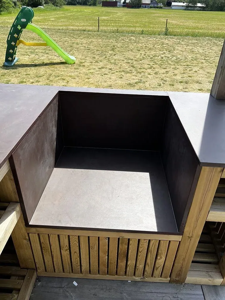 Matt bänkskiva i Dekton Kadum keramik i ett utekök i Påarp, monterad på träklädd bas med trädgård i bakgrunden.