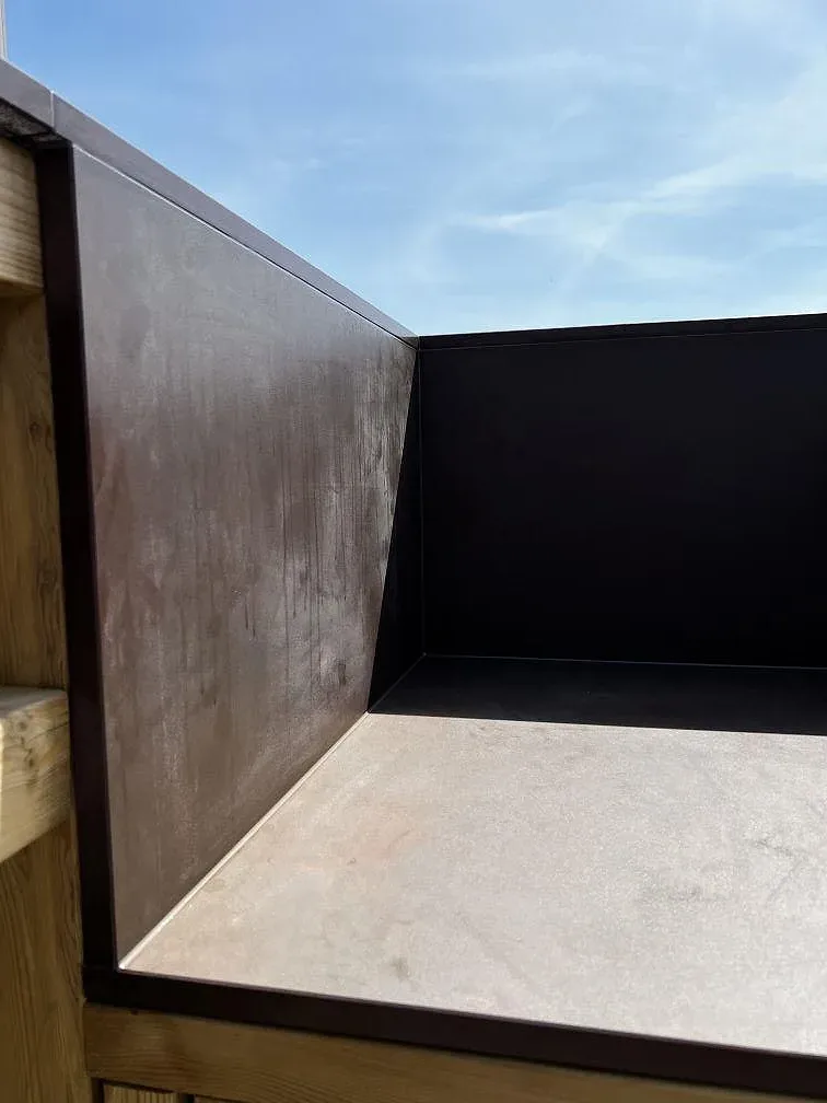Detalj av matt Dekton Kadum bänkskiva och sidostycken i ett utekök under montering i Påarp.